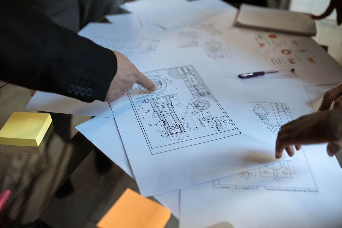 Handen boven bouwtekeningen tijdens een werkoverleg